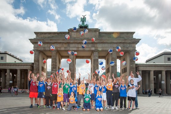 Eine ALBA-Kindermannschaft wirft vor dem Brandenburger Tor ihre Basketbälle gleichzeitig in die Luft. 