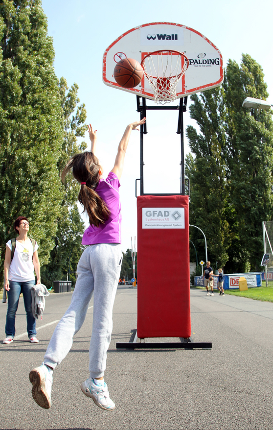 Ein Mädchen versucht einen Basketballkorb zu treffen.
